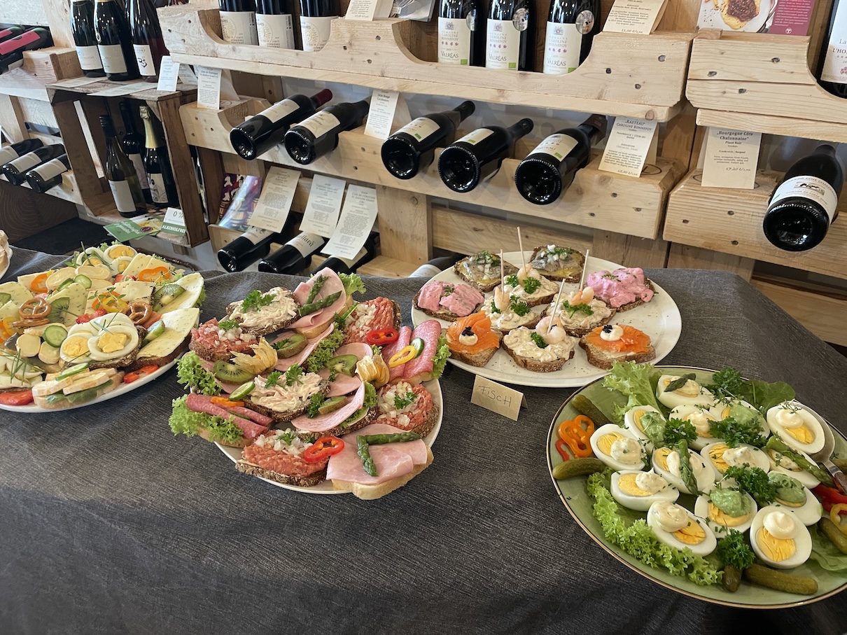 Ein Buffet aus Häppchen vor einem Weinregal.
